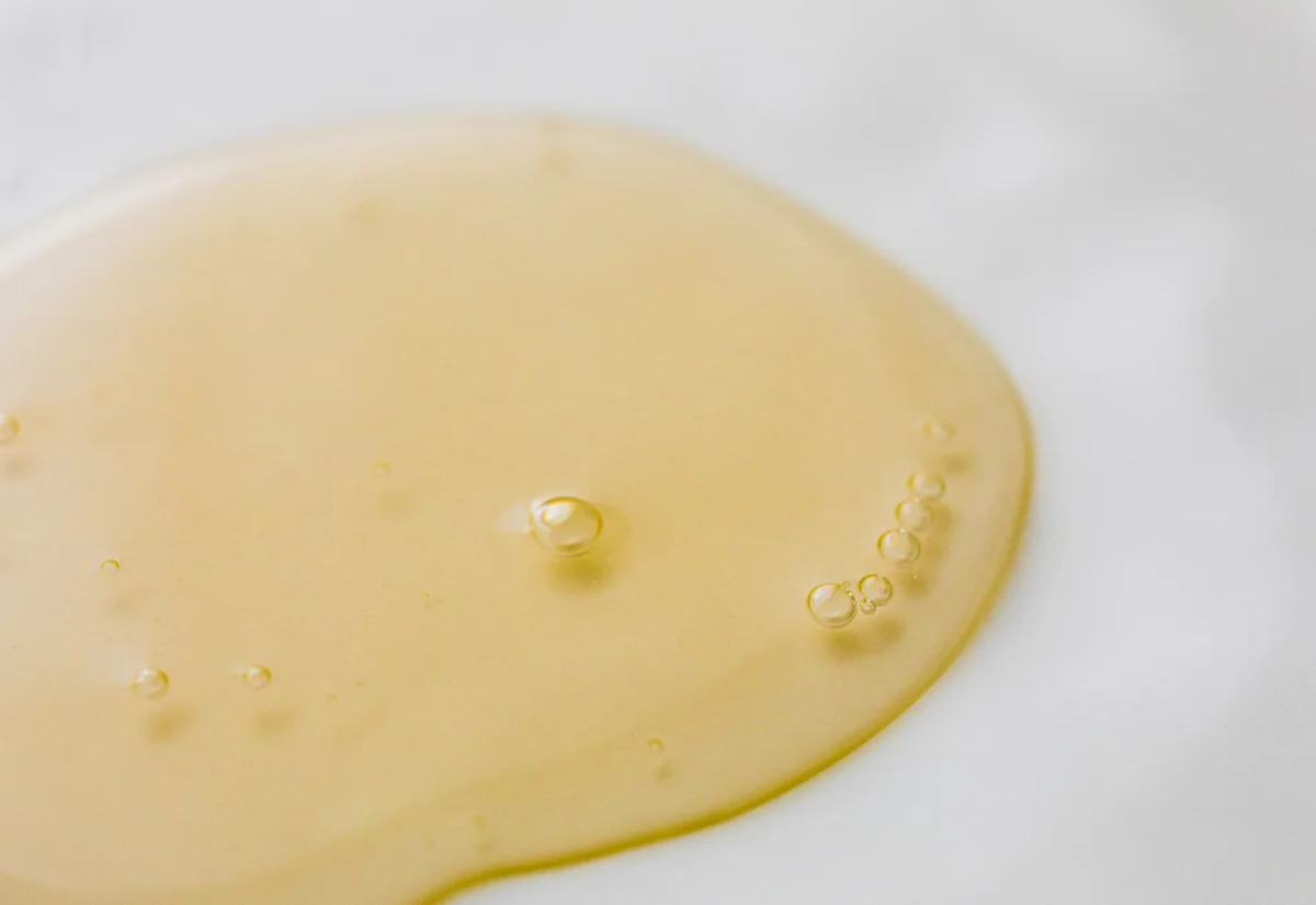 Textura de un sérum dorado sobre una superficie blanca